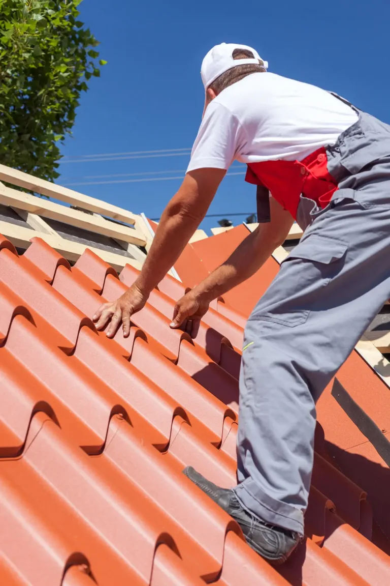 ASI Construction worker installing metal roof shingles on a slanted roof.